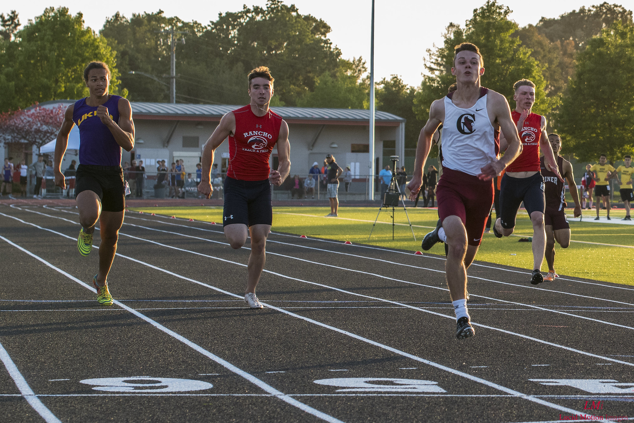 Athlete prepares for pole vault on a track with others watching.