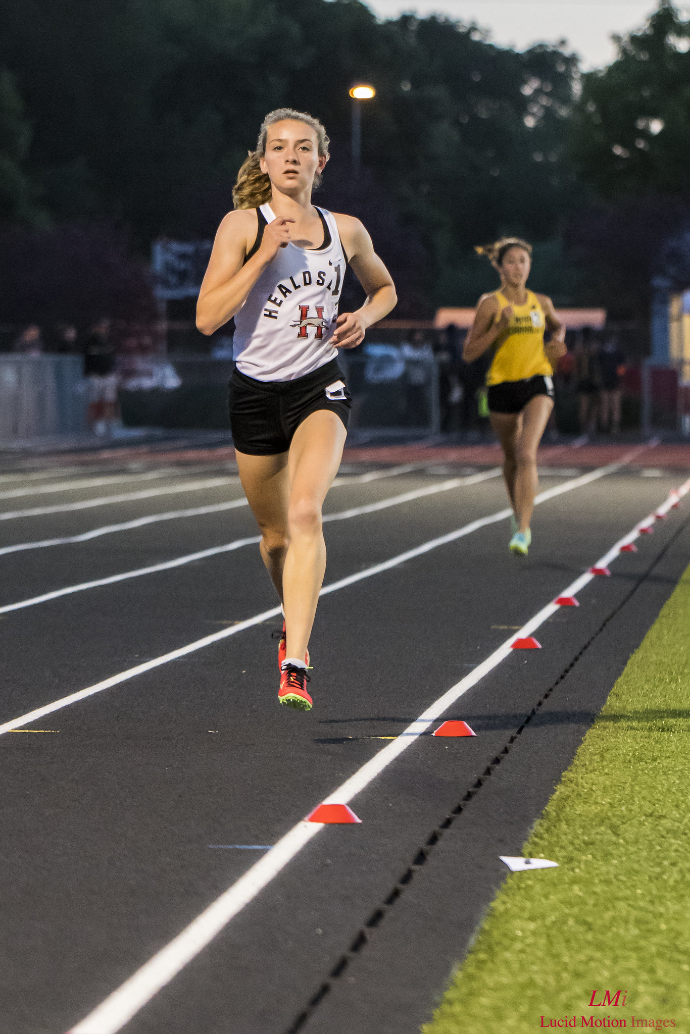 Athlete prepares for pole vault on a track with others watching.