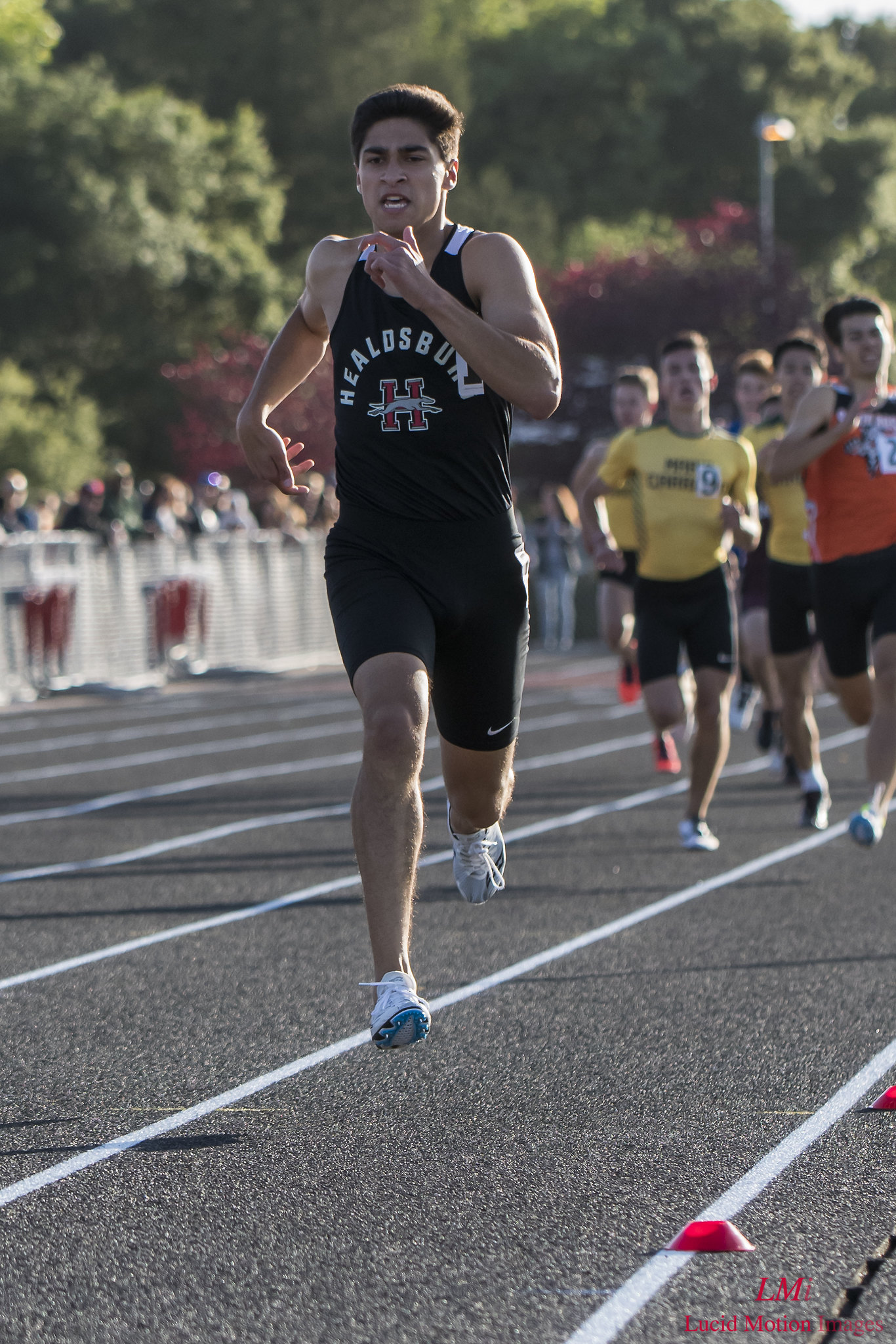 Athlete prepares for pole vault on a track with others watching.