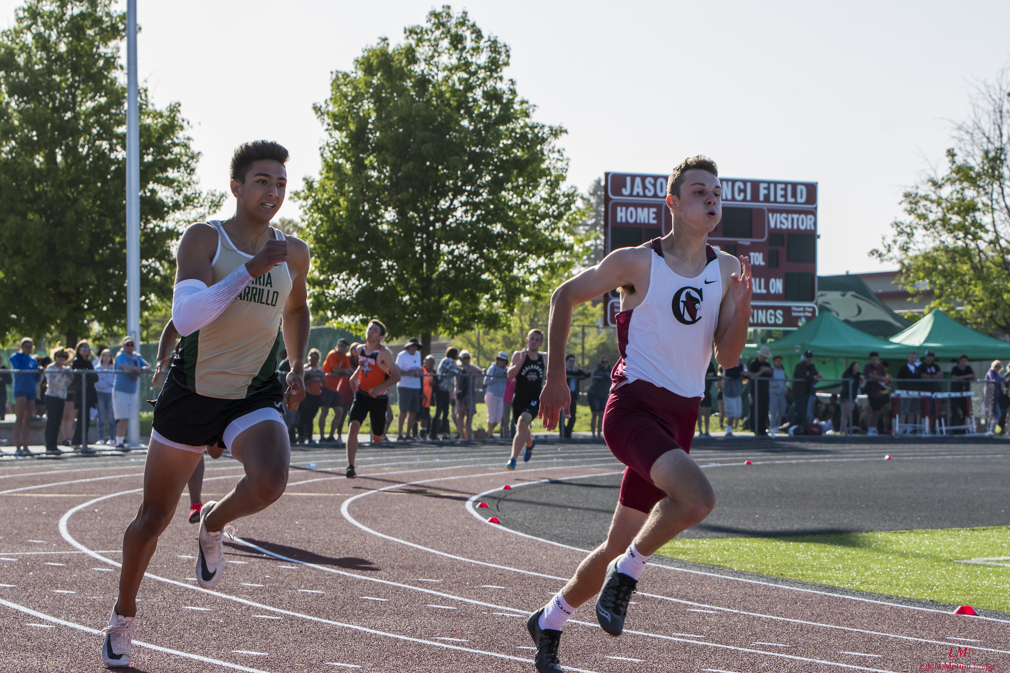 Athlete prepares for pole vault on a track with others watching.