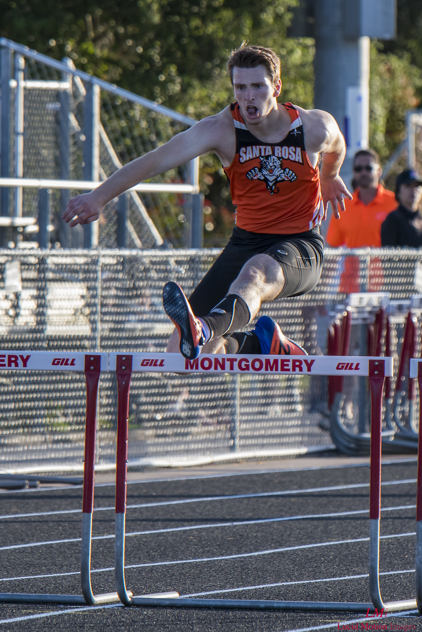 Athlete prepares for pole vault on a track with others watching.