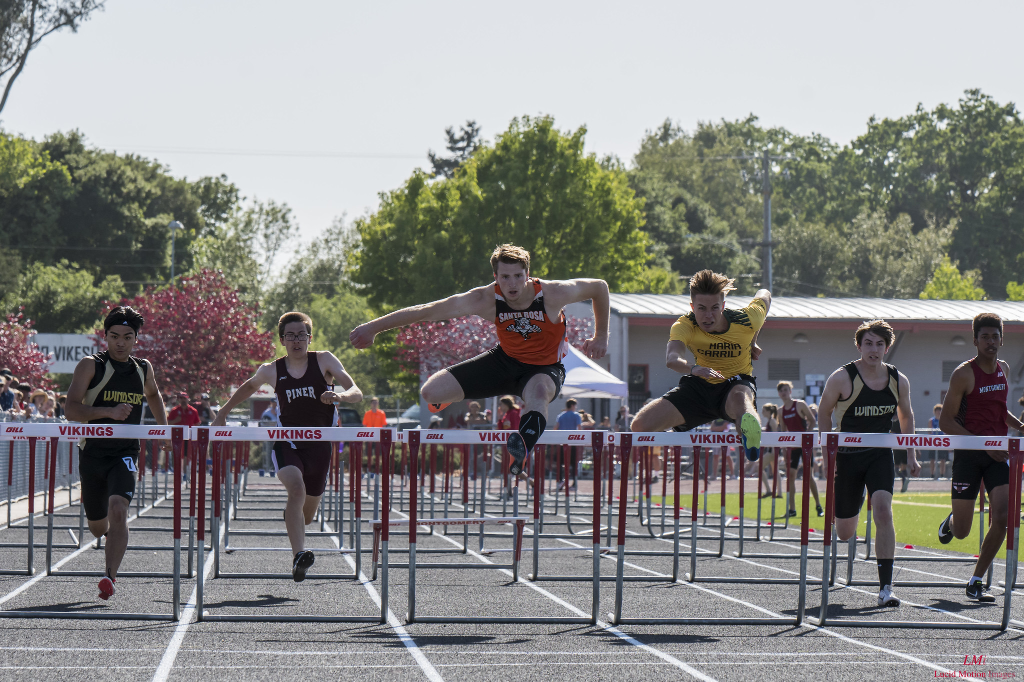 Athlete prepares for pole vault on a track with others watching.