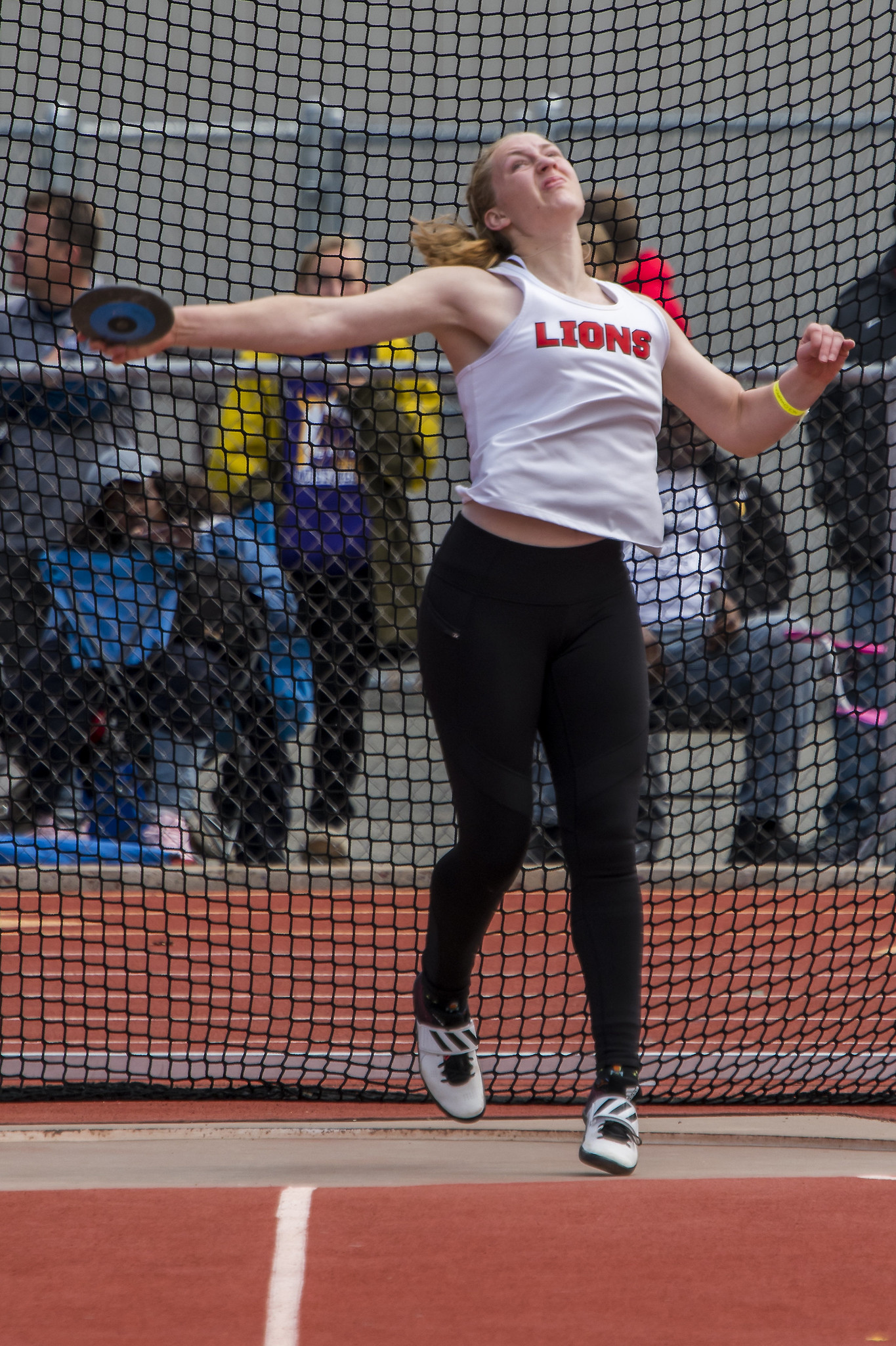 Athlete prepares for pole vault on a track with others watching.