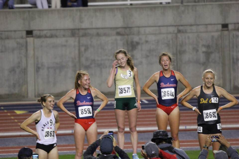 Athlete prepares for pole vault on a track with others watching.