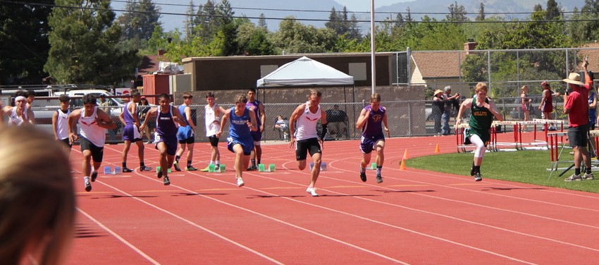 Athlete prepares for pole vault on a track with others watching.