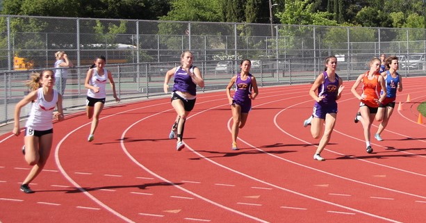 Athlete prepares for pole vault on a track with others watching.
