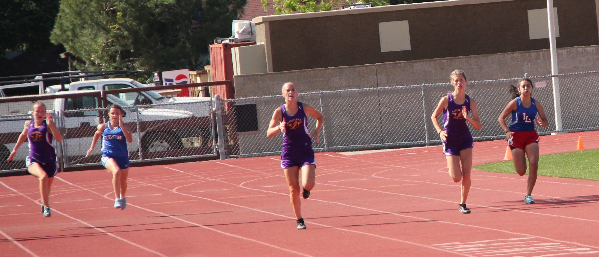 Athlete prepares for pole vault on a track with others watching.