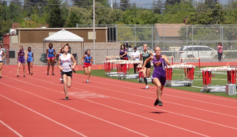 Athlete prepares for pole vault on a track with others watching.