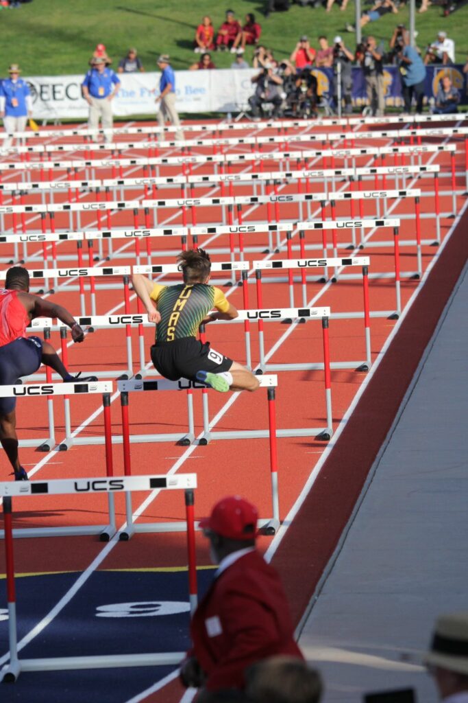 Athlete prepares for pole vault on a track with others watching.