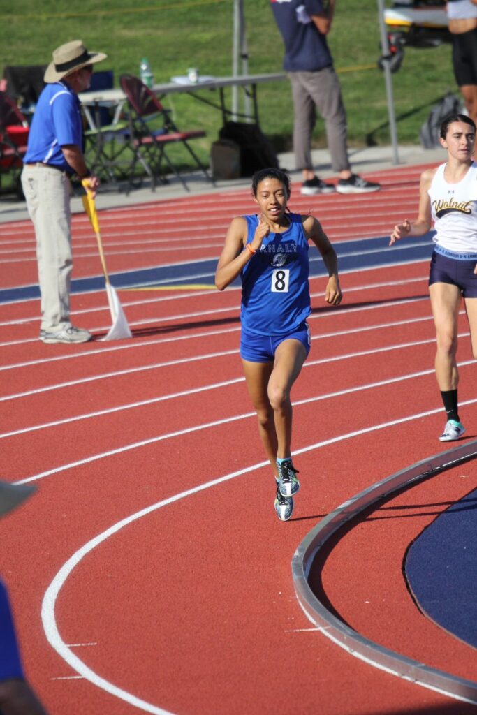 Athlete prepares for pole vault on a track with others watching.