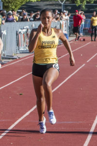 Athlete prepares for pole vault on a track with others watching.