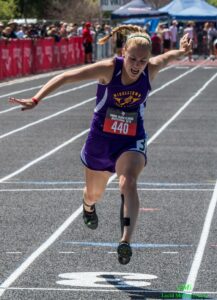Athlete prepares for pole vault on a track with others watching.