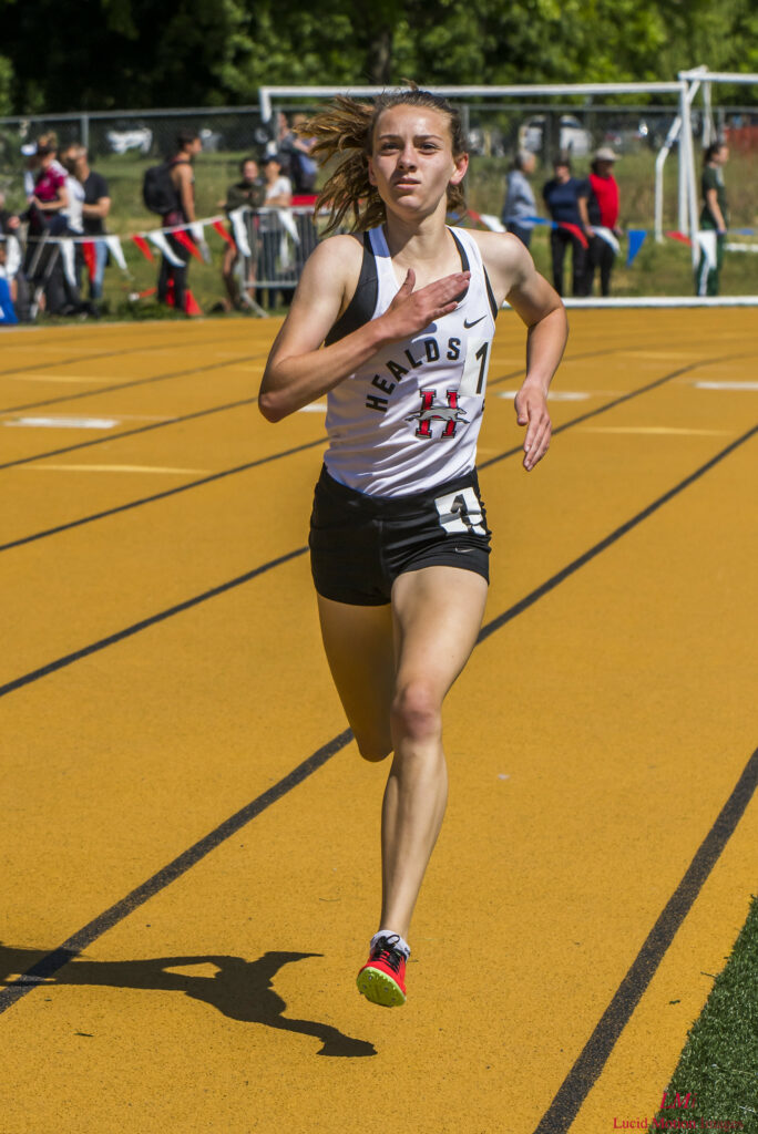Athlete prepares for pole vault on a track with others watching.