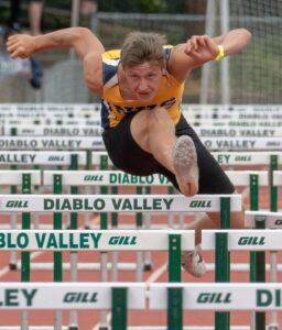 Athlete prepares for pole vault on a track with others watching.