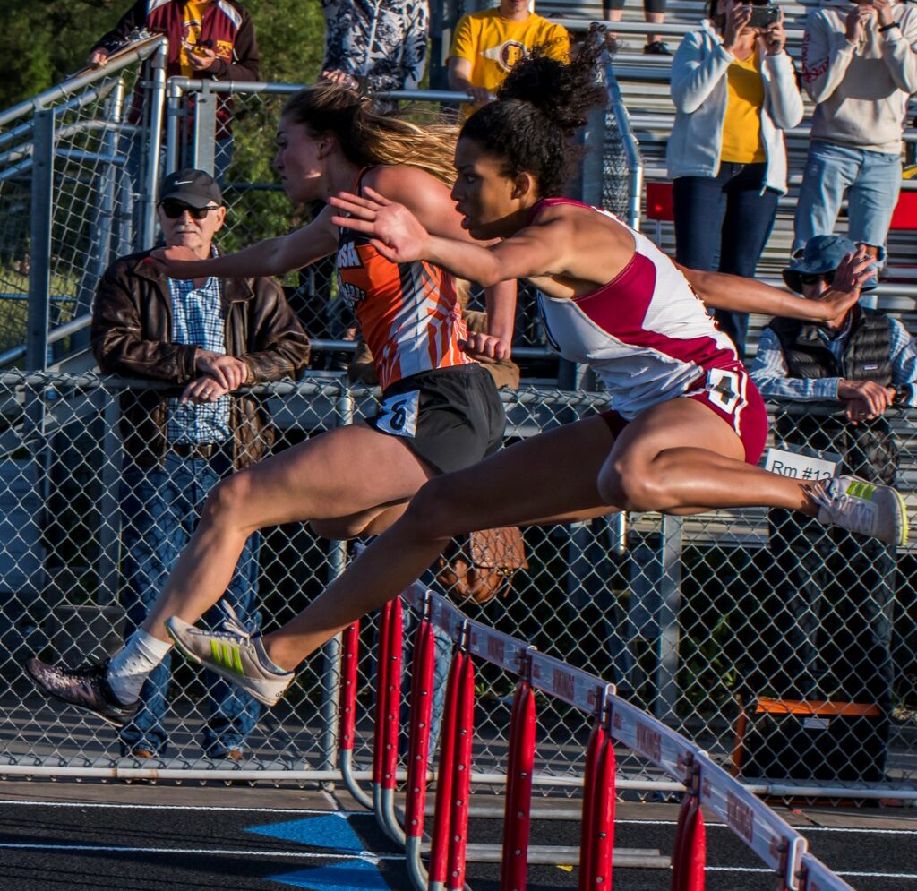Athlete prepares for pole vault on a track with others watching.