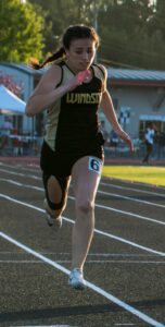 Athlete prepares for pole vault on a track with others watching.