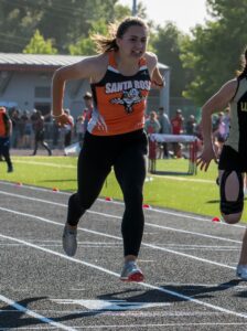 Athlete prepares for pole vault on a track with others watching.