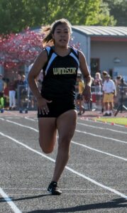 Athlete prepares for pole vault on a track with others watching.