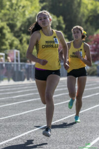Athlete prepares for pole vault on a track with others watching.