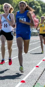 Athlete prepares for pole vault on a track with others watching.