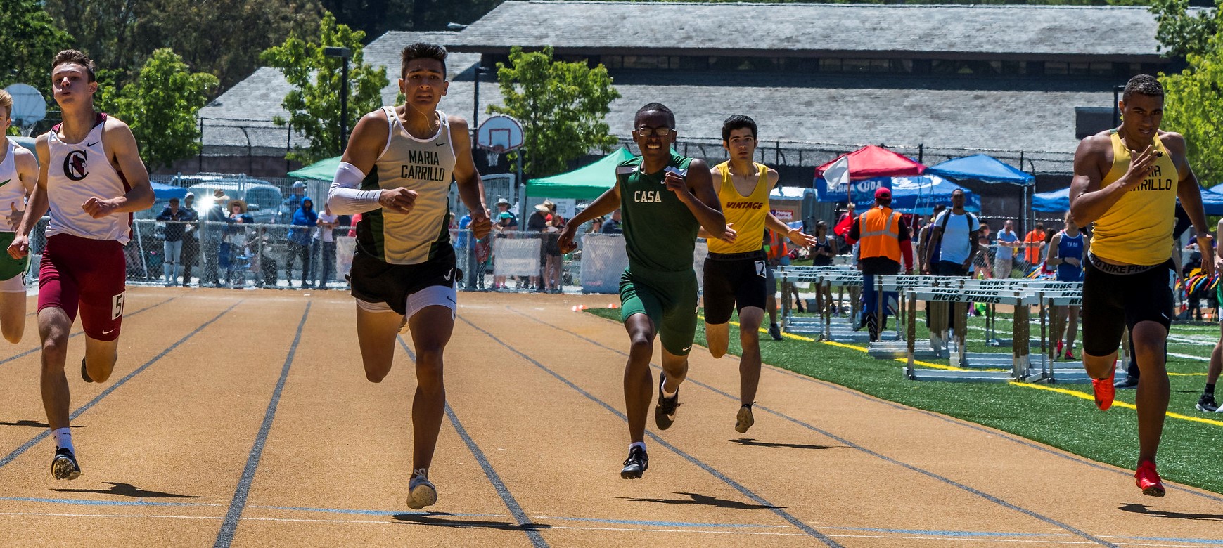 Athlete prepares for pole vault on a track with others watching.