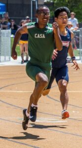 Athlete prepares for pole vault on a track with others watching.