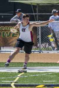 Athlete prepares for pole vault on a track with others watching.
