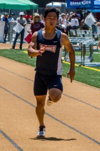 Athlete prepares for pole vault on a track with others watching.
