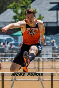 Athlete prepares for pole vault on a track with others watching.