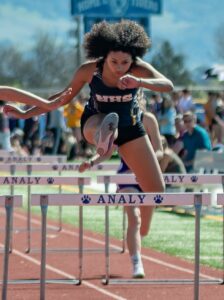 Athlete prepares for pole vault on a track with others watching.