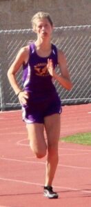 Athlete prepares for pole vault on a track with others watching.