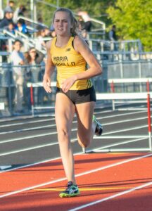 Athlete prepares for pole vault on a track with others watching.
