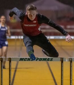 Athlete prepares for pole vault on a track with others watching.