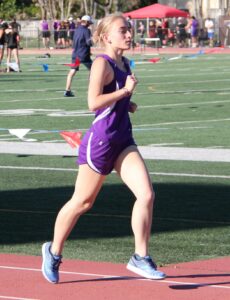 Athlete prepares for pole vault on a track with others watching.