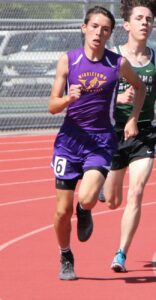 Athlete prepares for pole vault on a track with others watching.