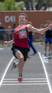 Athlete prepares for pole vault on a track with others watching.