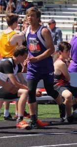 Athlete prepares for pole vault on a track with others watching.