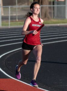 Athlete prepares for pole vault on a track with others watching.