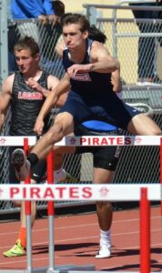 Athlete prepares for pole vault on a track with others watching.