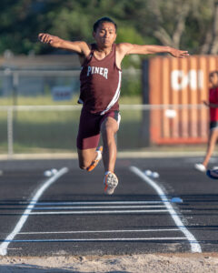 Athlete prepares for pole vault on a track with others watching.