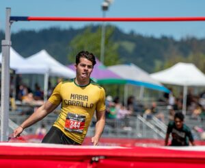 Athlete prepares for pole vault on a track with others watching.