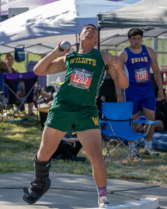 Athlete prepares for pole vault on a track with others watching.