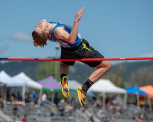 Athlete prepares for pole vault on a track with others watching.