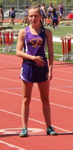 Athlete prepares for pole vault on a track with others watching.