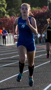 Athlete prepares for pole vault on a track with others watching.
