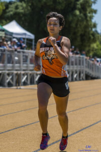Athlete prepares for pole vault on a track with others watching.