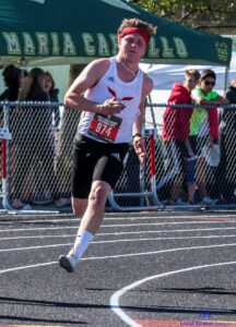 Athlete prepares for pole vault on a track with others watching.