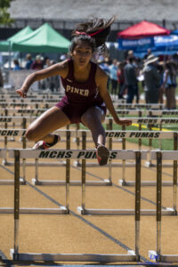 Athlete prepares for pole vault on a track with others watching.