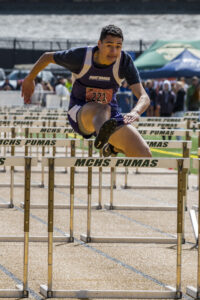 Athlete prepares for pole vault on a track with others watching.