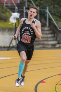 Athlete prepares for pole vault on a track with others watching.
